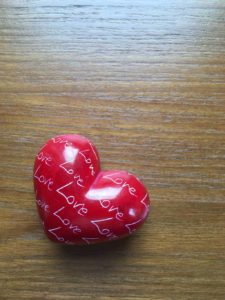 Small red heart-shaped paperweight inscribed all over with the word 'Love'
