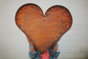 Girl holding large rusty metal heart
