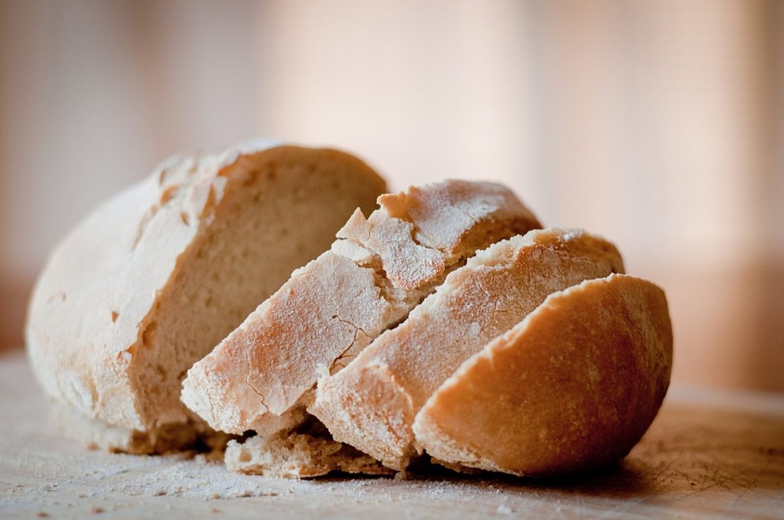 A loaf of crusty sourdough bread partially sliced