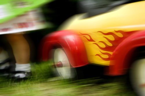 Blurred image of child's yellow and red ride-in car