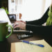 Image of woman using laptop and a green mug