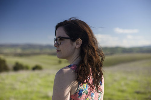 Image of young woman standing in field looking over shoulder