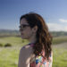 Image of young woman standing in field looking over shoulder