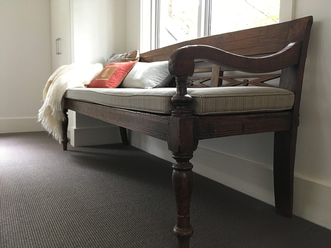 Old mahogany bench with cushions and throw