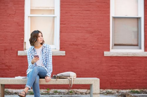 Young woman sitting on concrete bench, waiting